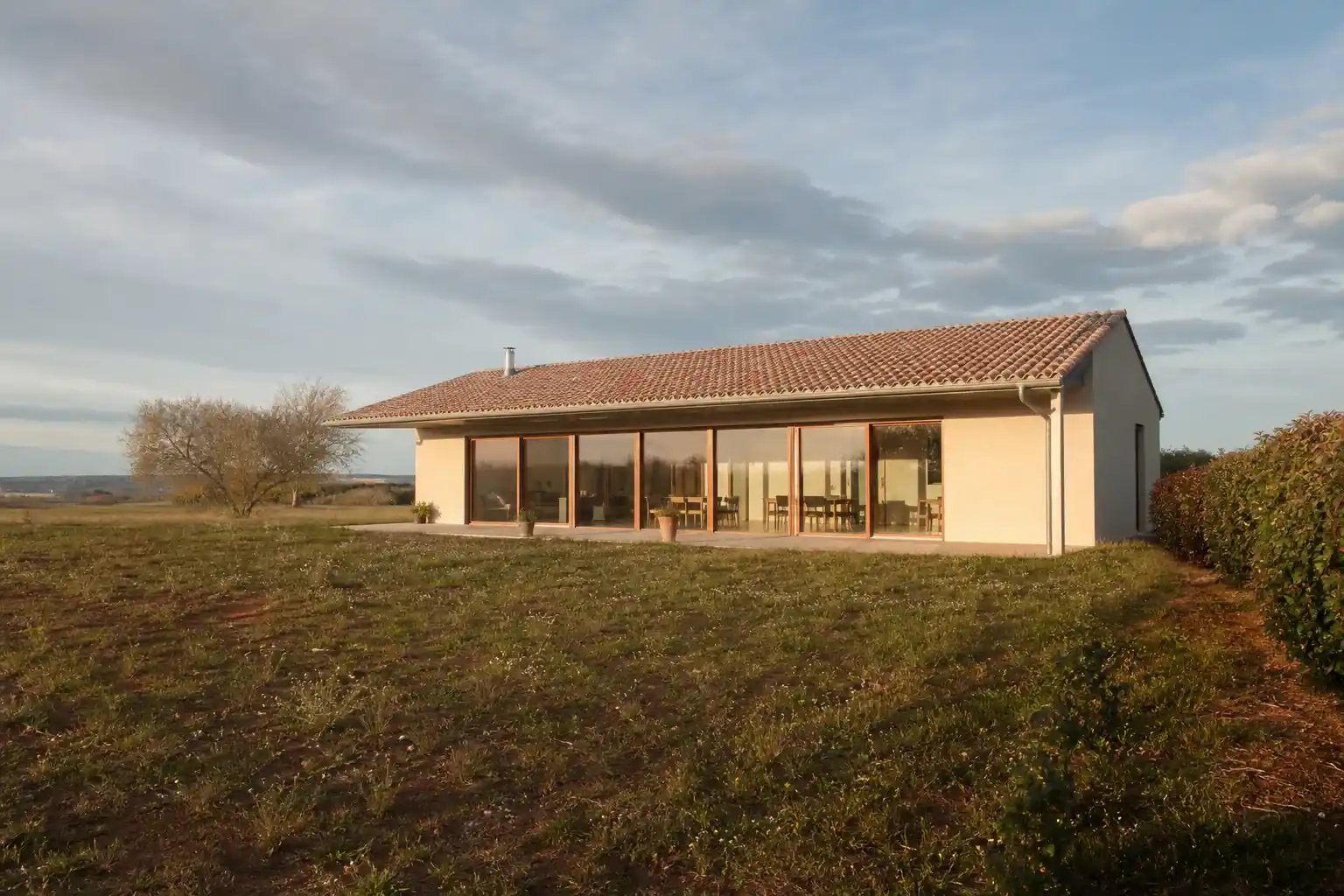 Parcelle large en terre agricole au sud-ouest de Toulouse, maison neuve orientée baies au sud, débord de toiture ombrant les vitrages